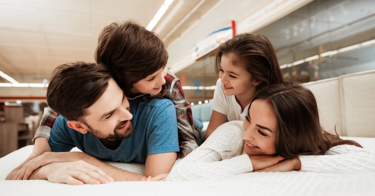family laying on alaskan king oversized mattress